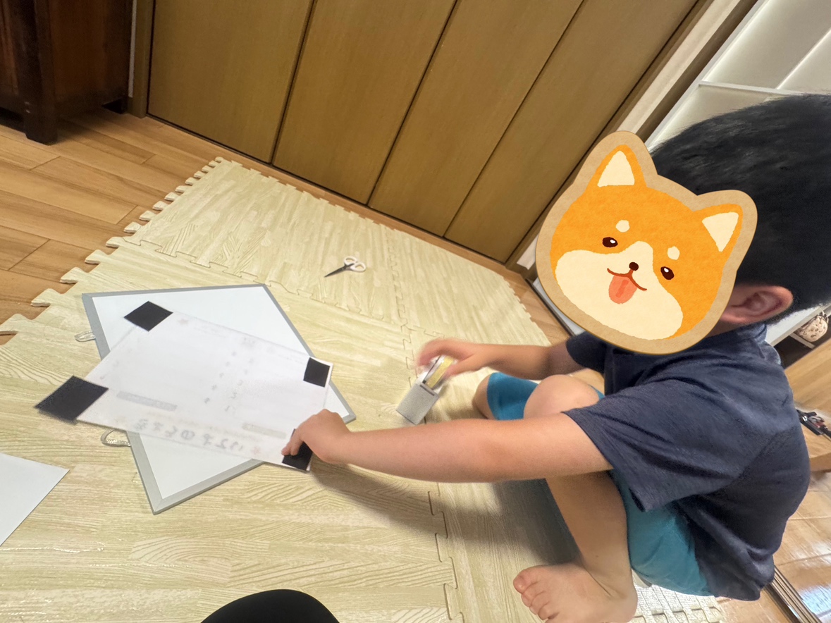 床に座って、テープやはさみを使った工作に取り組むお子さん