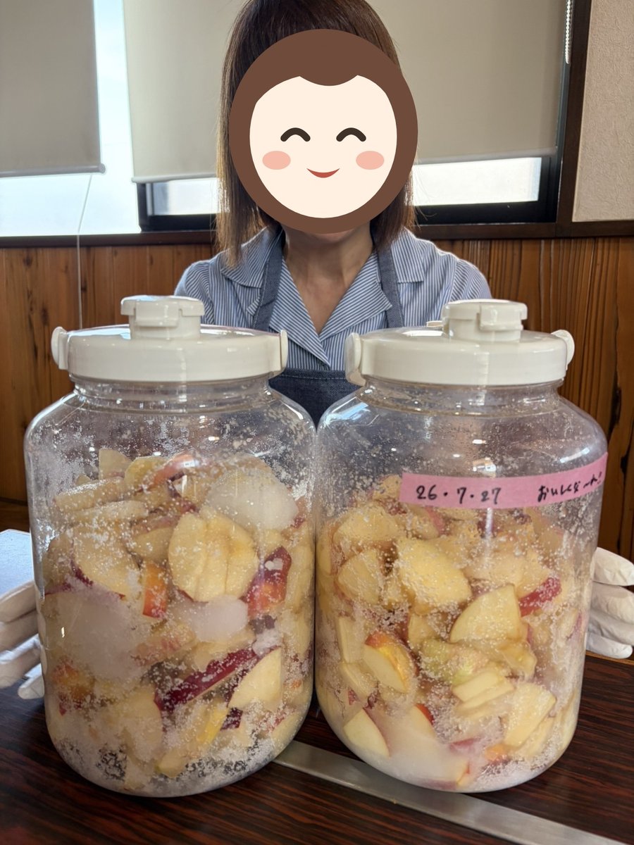 仕込みを終えた発酵ドリンクのボトル2本を持つスタッフ(顔はイラストで隠しています)