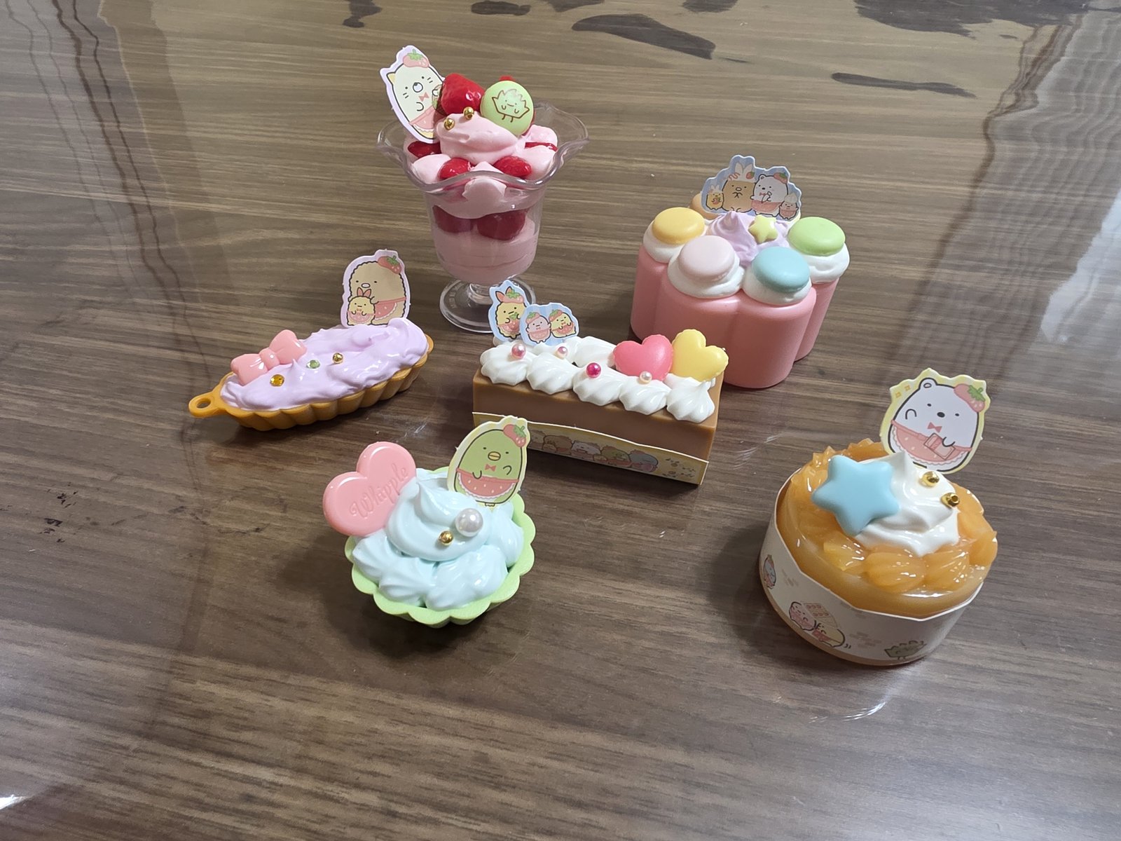 パフェ、マカロンのケーキ、エクレア、カップケーキなど、スイーツを模した工作作品6点。キャラクターのピックが添えてある