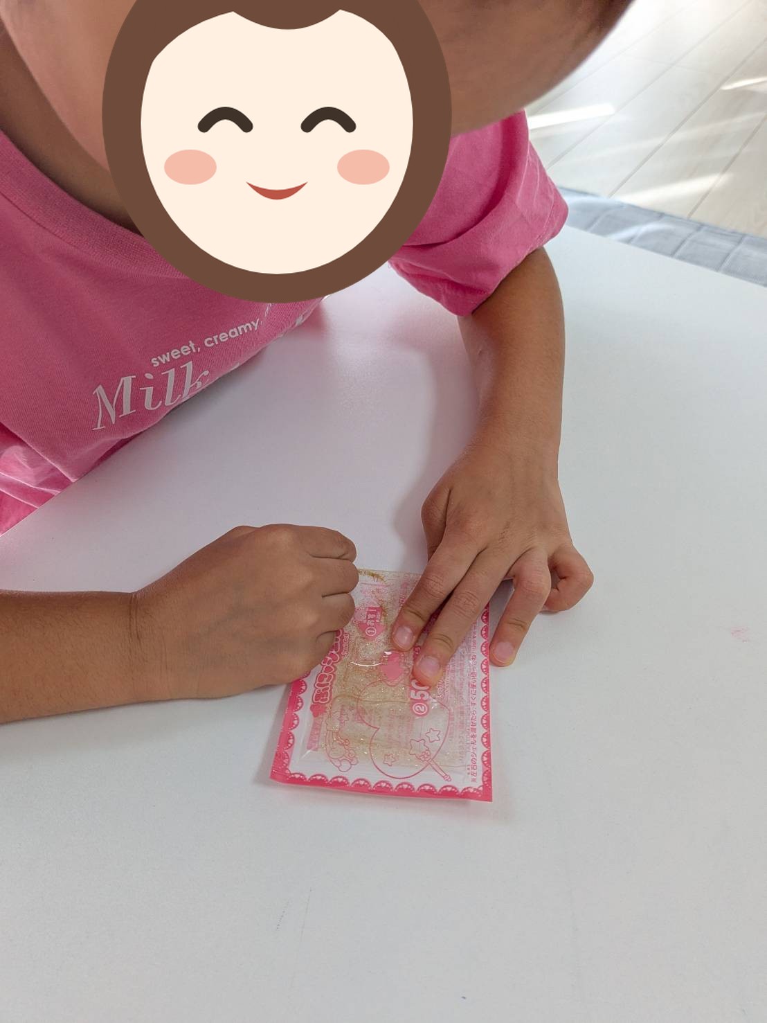 お子さんが机の上のパックを、両手の指先で押している手元の写真