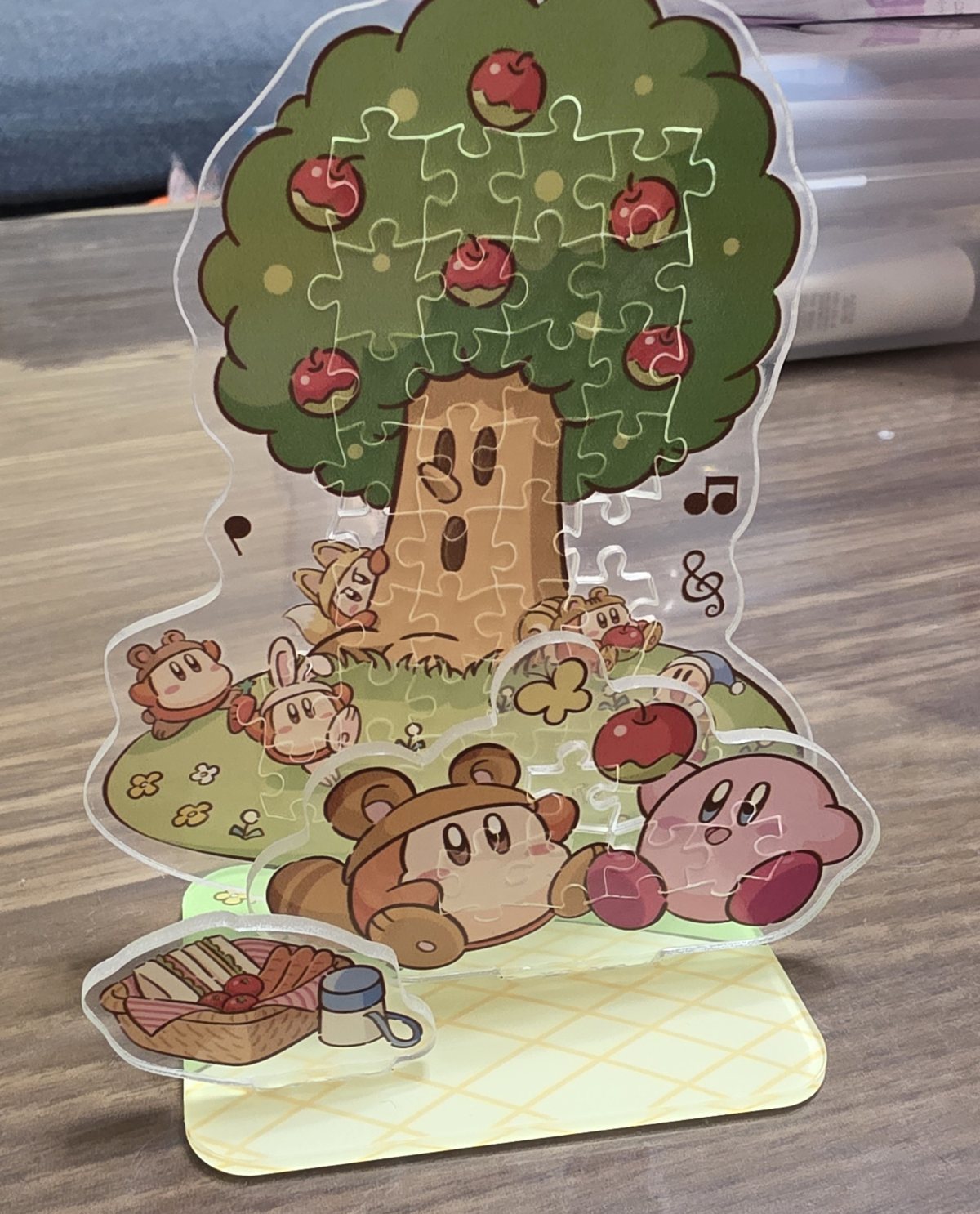 透明なピースを組み合わせて絵柄を完成させ、台座に立てたパズルのアクリルスタンド